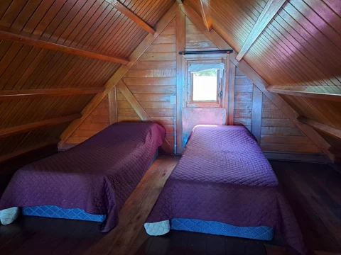 El altillo de la cabaña para 6 personas, con dos camas bajo el techo de madera a dos aguas