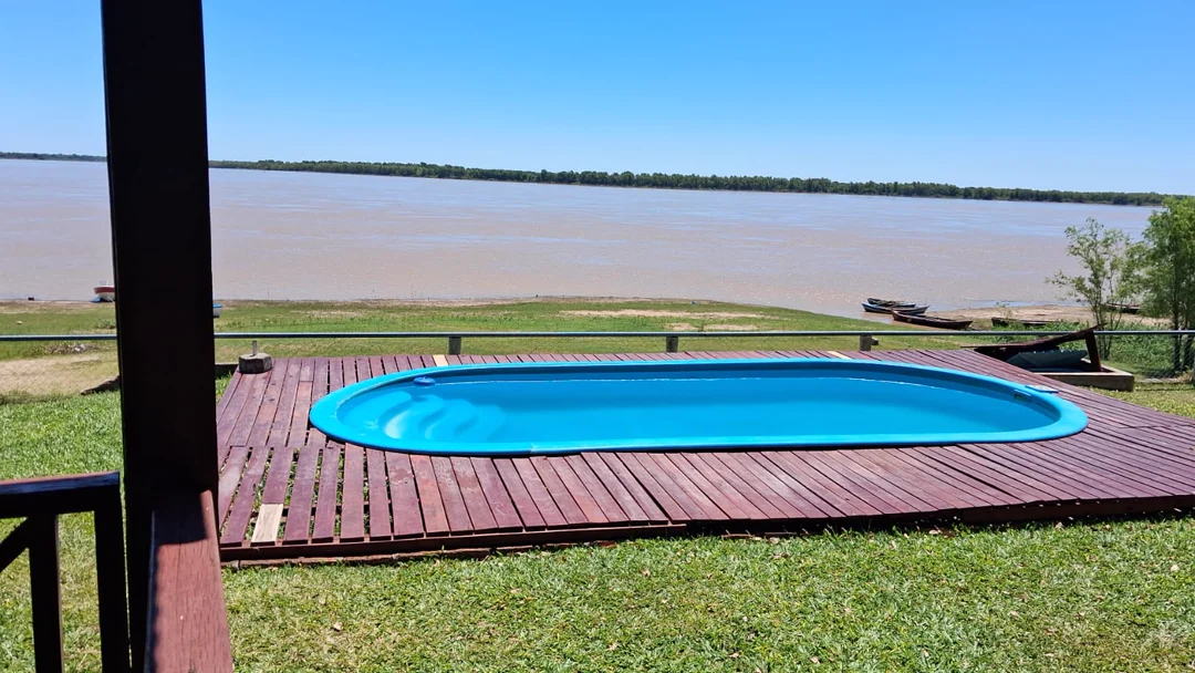 La pileta sobre el deck de madera de una cabaña, con el río Paraná de punta a punta al fondo, en Cabañas de Hugo, Pueblo Brugo